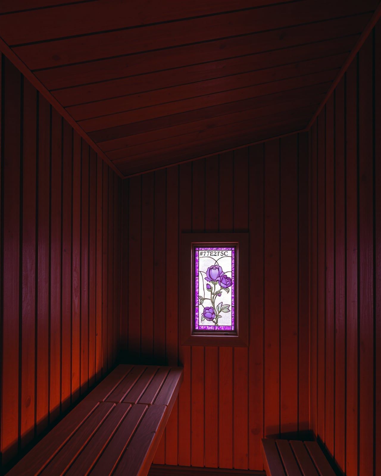 A free-standing wood-fired sauna cabin in the Hudson Valley hemlocks at dusk — thermo-aspen siding, a single brass-banded chimney, lantern light from the dressing room window onto frost-stiff grass